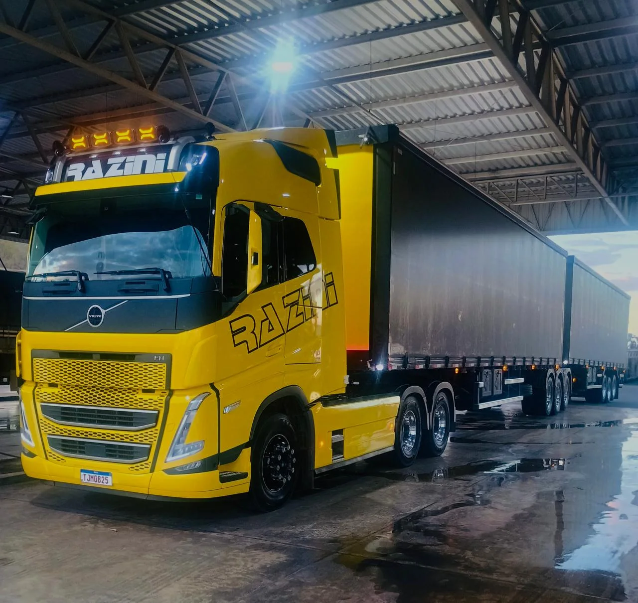 Rodotrem amarelo da Razini Transportes carregando em galpão coberto