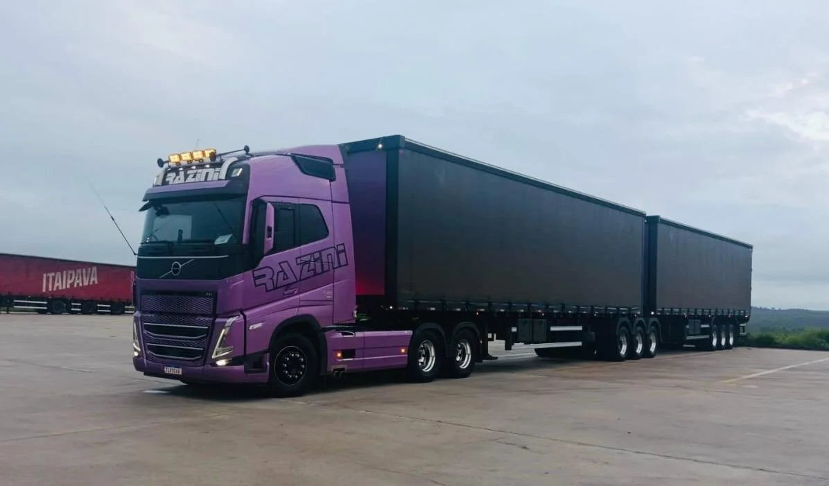 Rodotrem lilás da Razini, Volvo FH, com dois semirreboques em pátio de carga